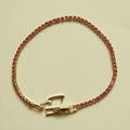 Gold-tone tennis bracelet with pink CZ stones and a rectangular clasp at center.