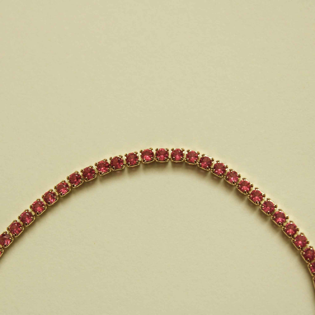 Pink CZ stone row on a gold-tone tennis bracelet, close-up of linked stones.