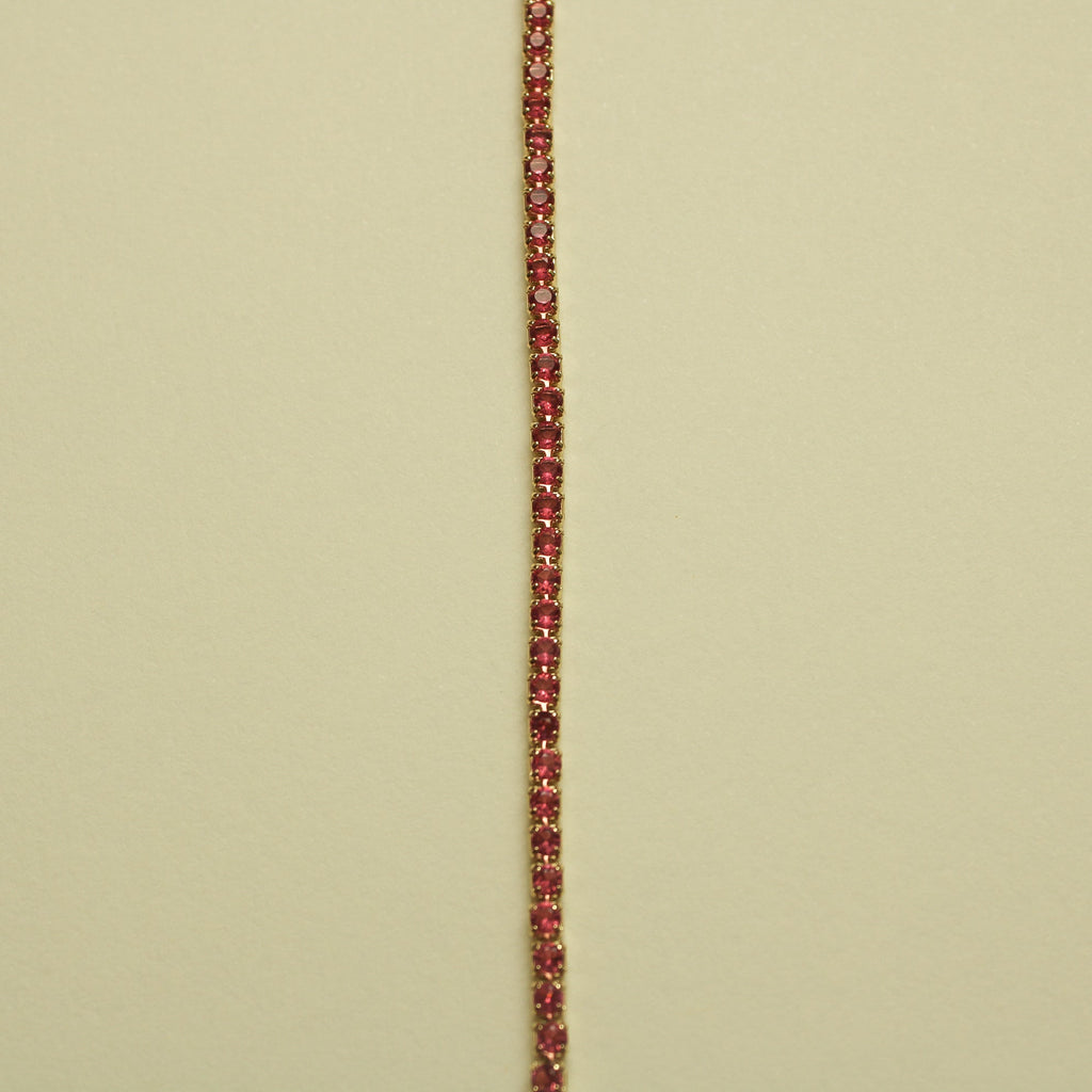 Gold-tone tennis bracelet with pink round CZ stones, stacked along the chain.