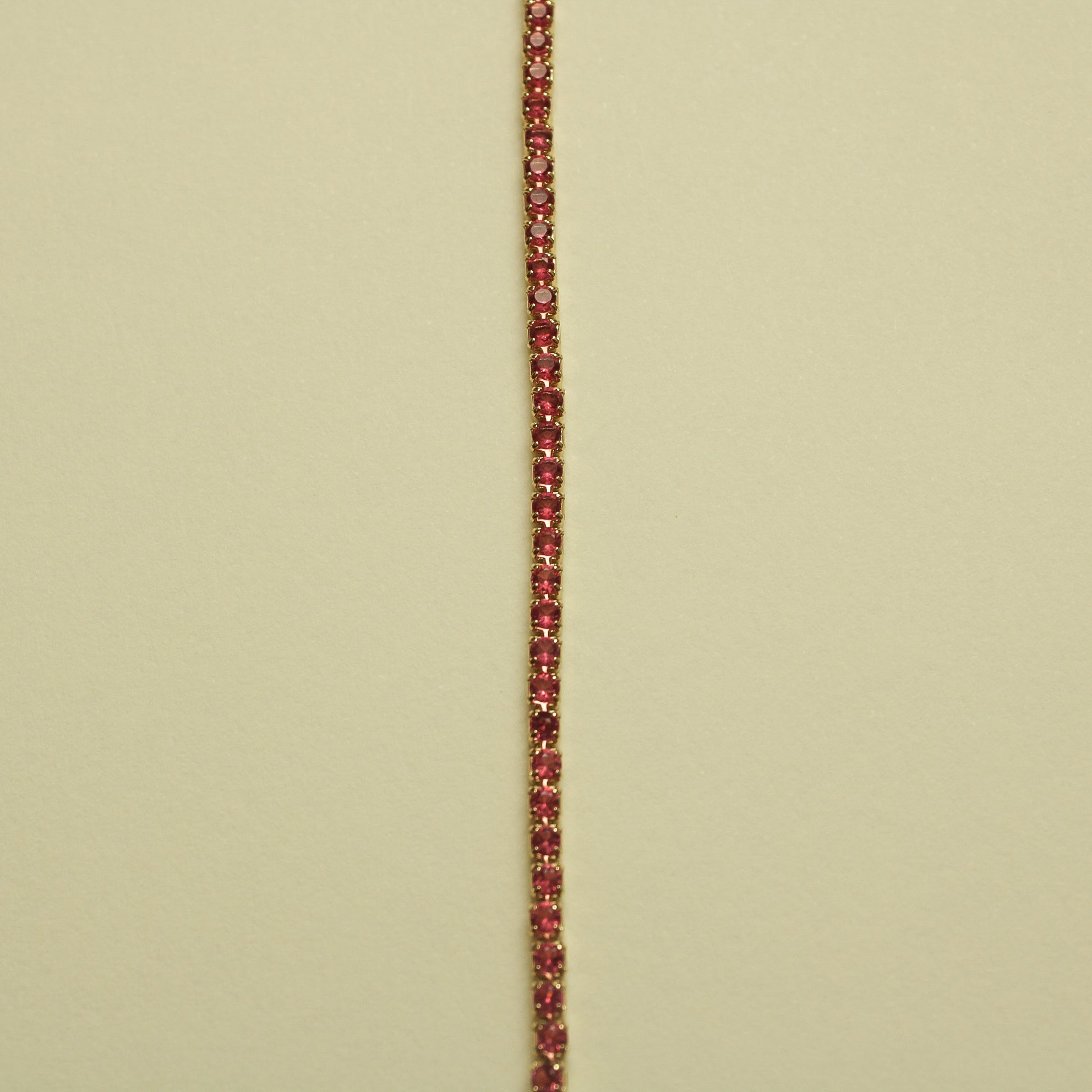 Gold-tone tennis bracelet with pink round CZ stones, stacked along the chain.