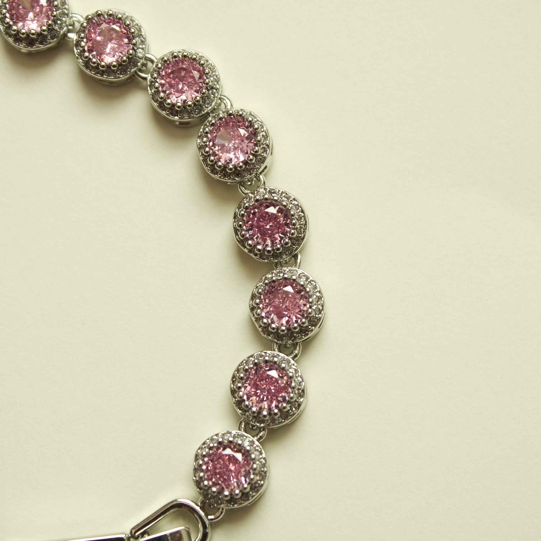 Pink halo CZ tennis bracelet strand with evenly spaced round stones and open clasp