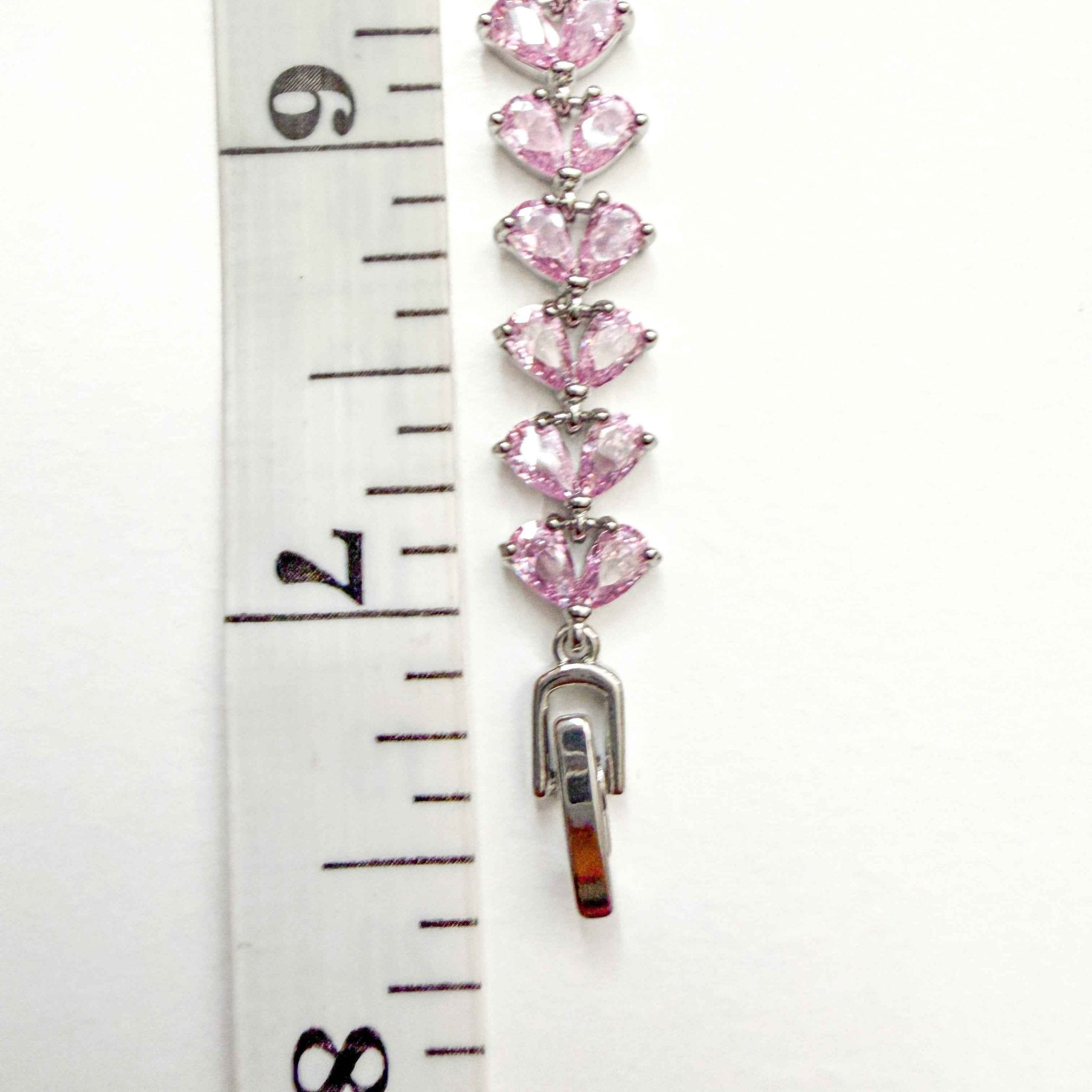 Pink CZ tennis bracelet with linked pear-shaped pink stones in silver prongs, close-up