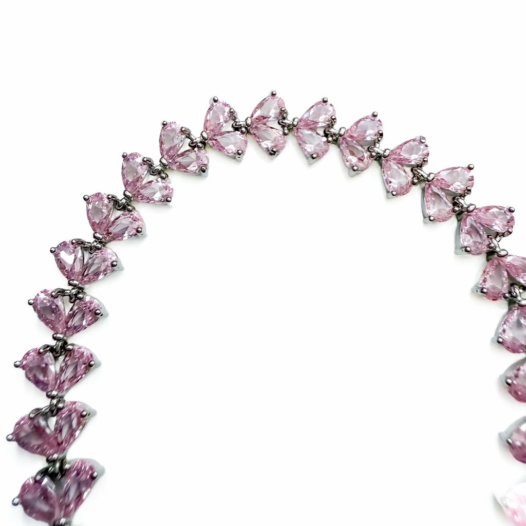 Pink CZ tennis bracelet with pear-shaped pink stones and silver prong links, partial view