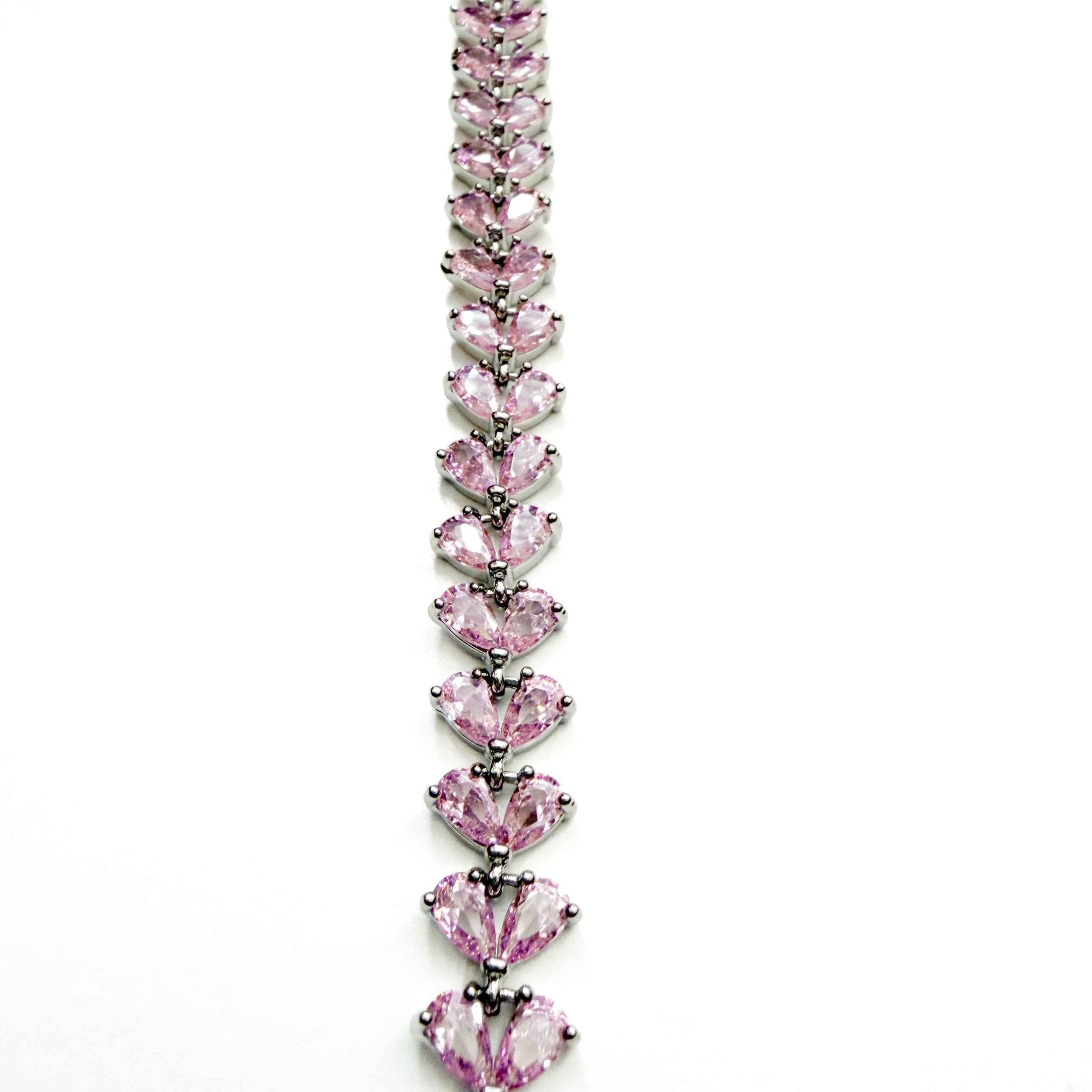 Pink CZ tennis bracelet with linked pear-shaped pink stones in silver prong settings, angled view