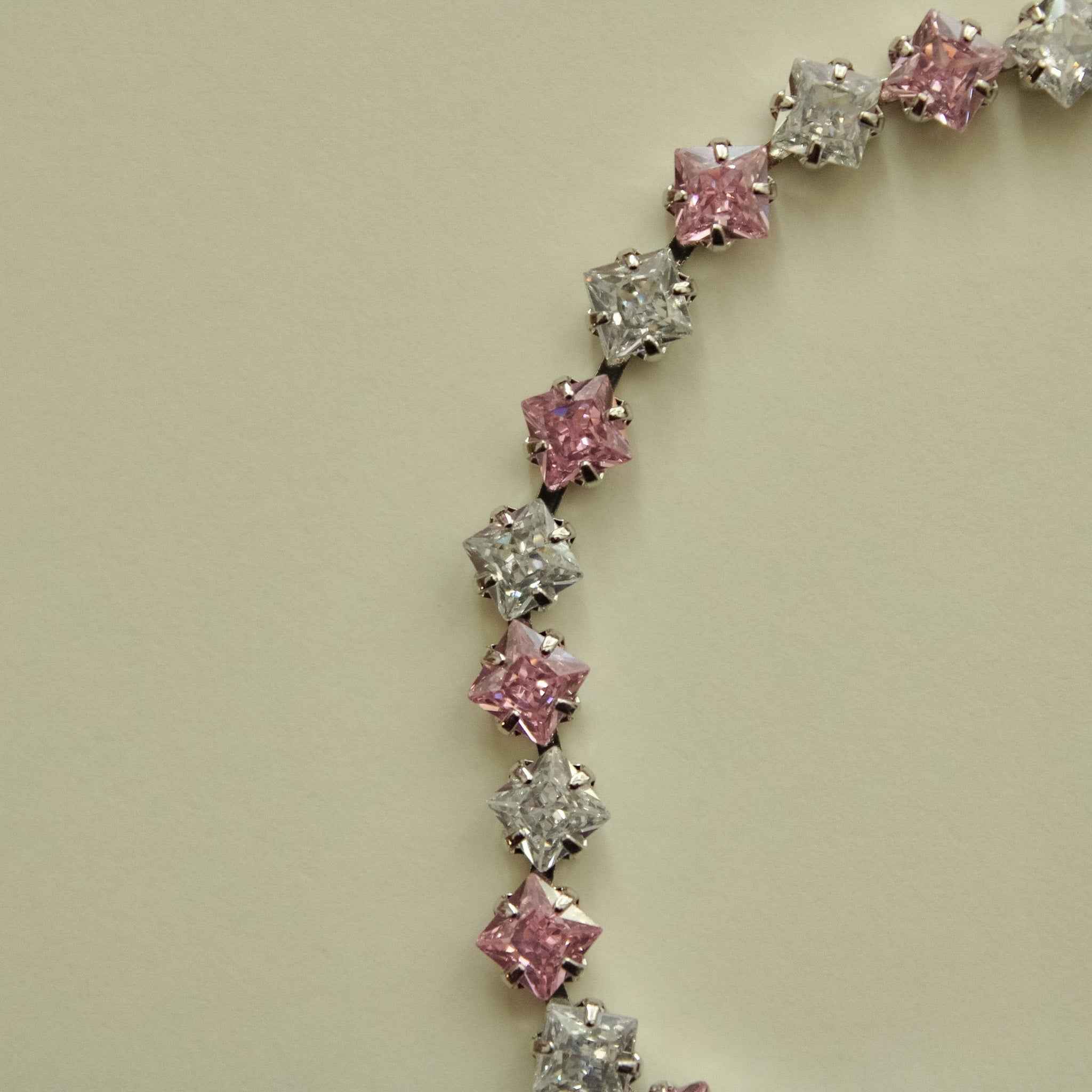 Tennis bracelet link closeup with alternating pink and clear CZ princess cuts