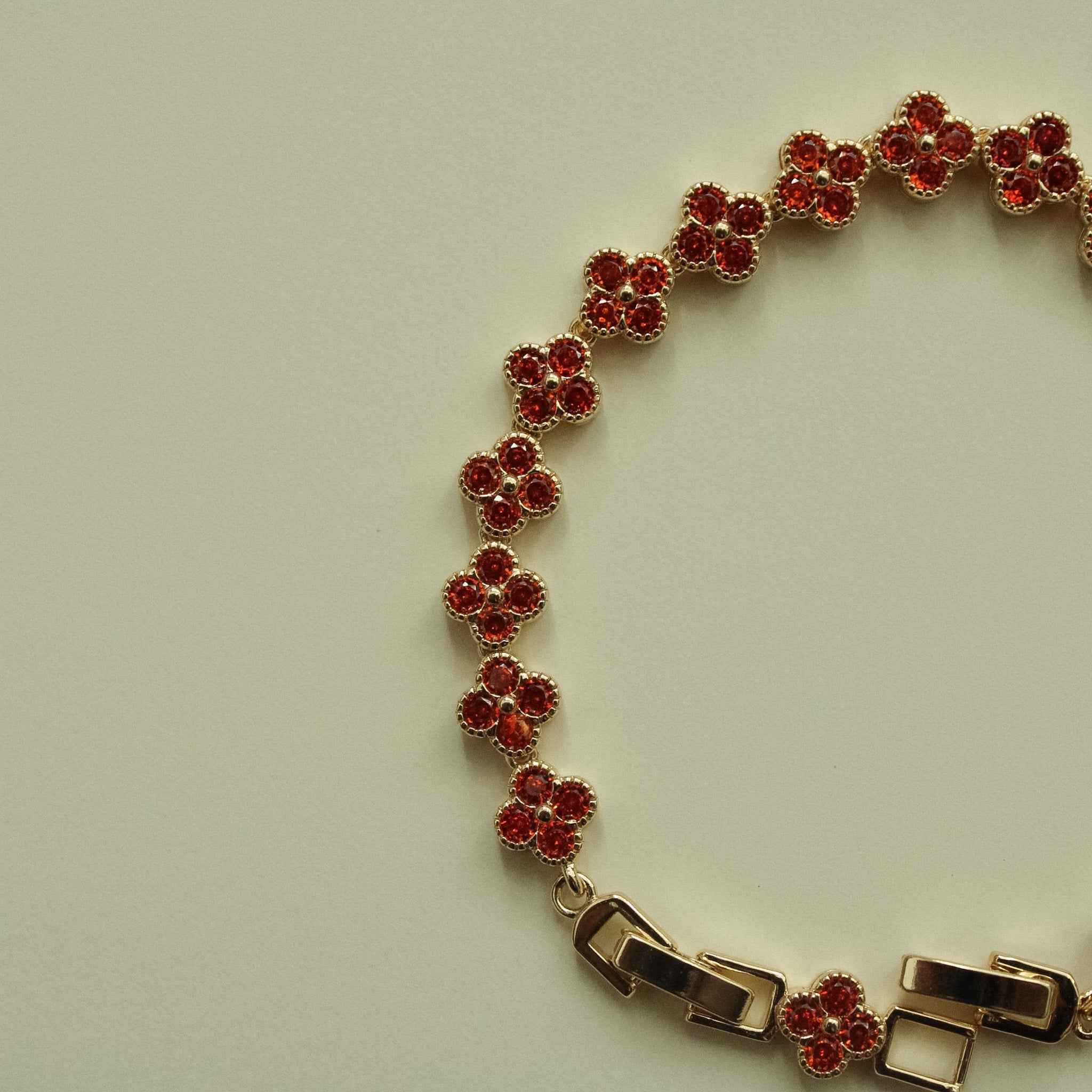 Gold-tone bracelet with red CZ flower links and toggle clasp with two end bars