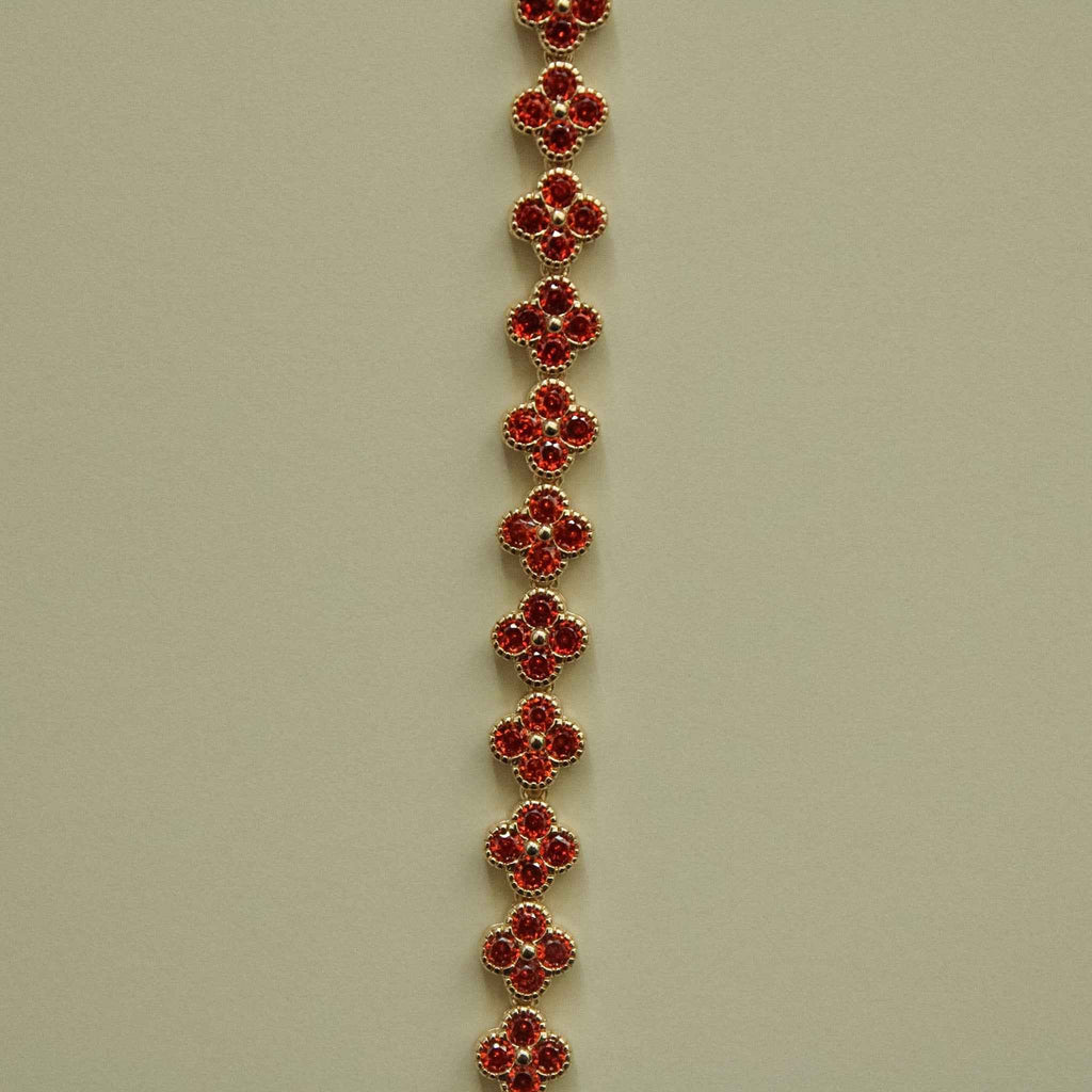 Gold-tone bracelet with evenly spaced red round CZ flower links along the strand
