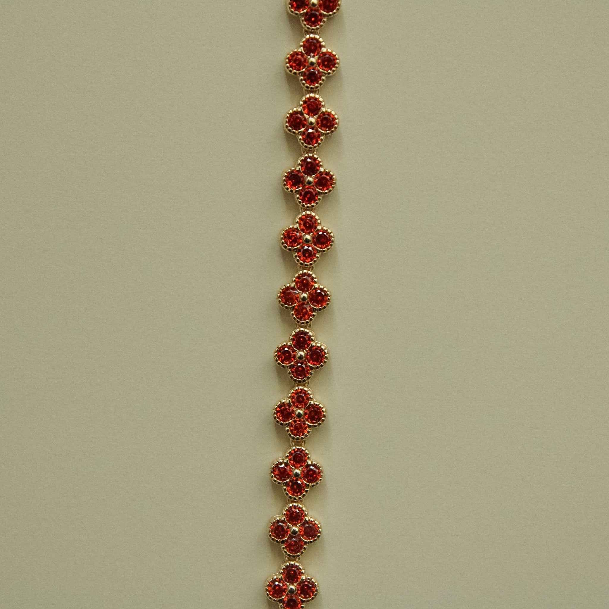 Gold-tone bracelet with evenly spaced red round CZ flower links along the strand