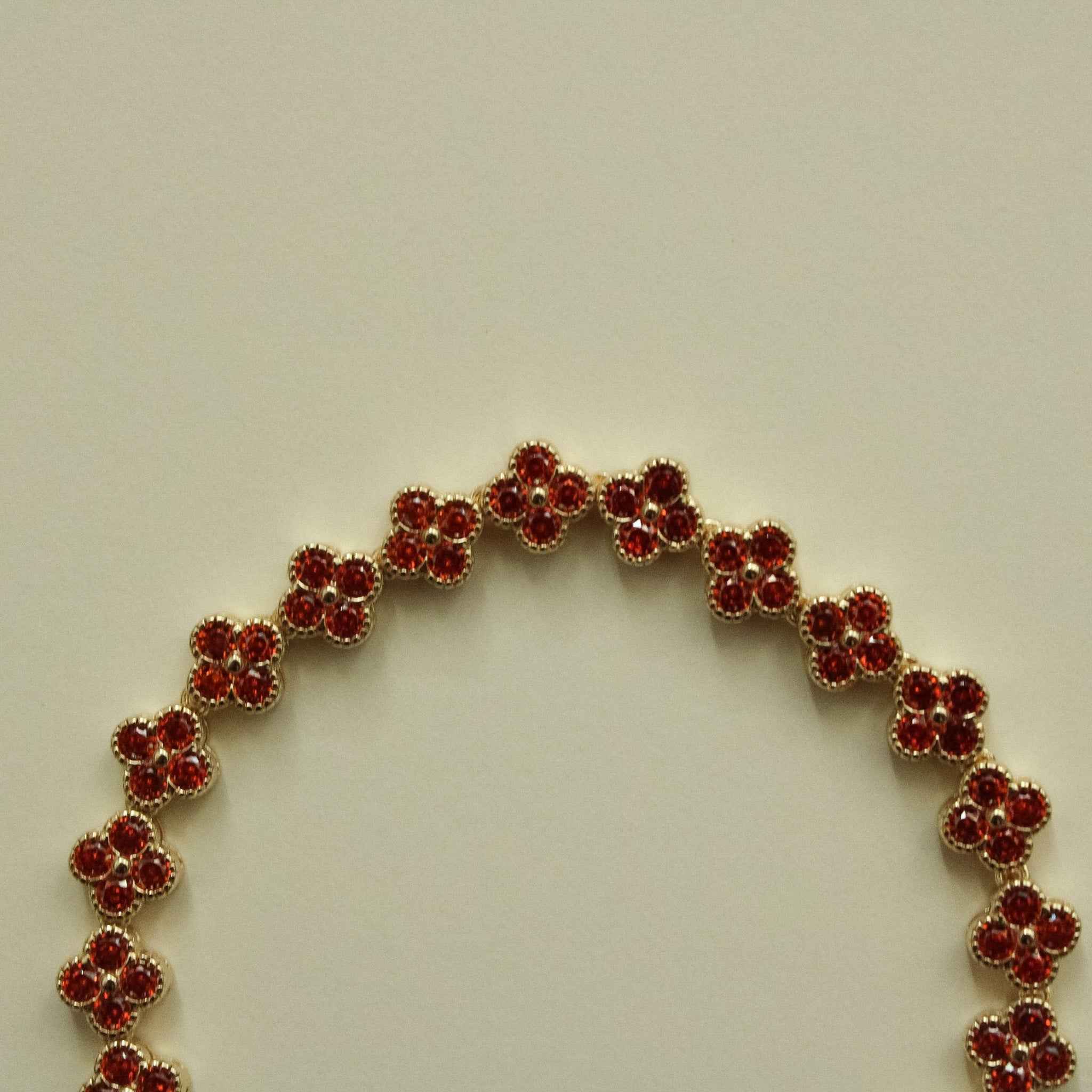 Gold-tone bracelet with red round CZ flower links, curved openwork section