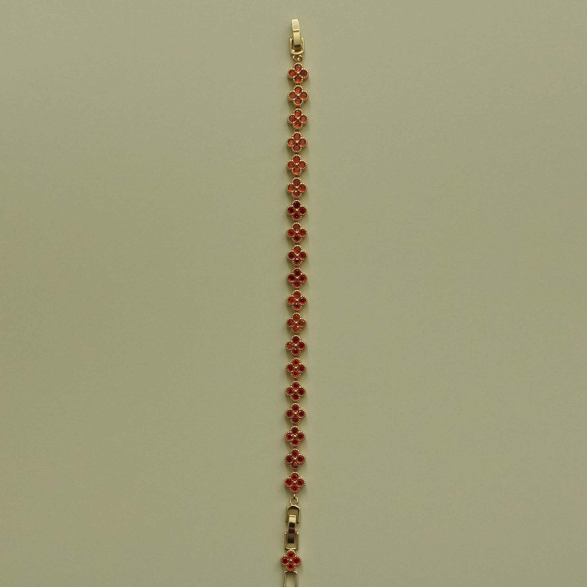 Gold-tone tennis bracelet with red CZ flower bead row and small clasp at top