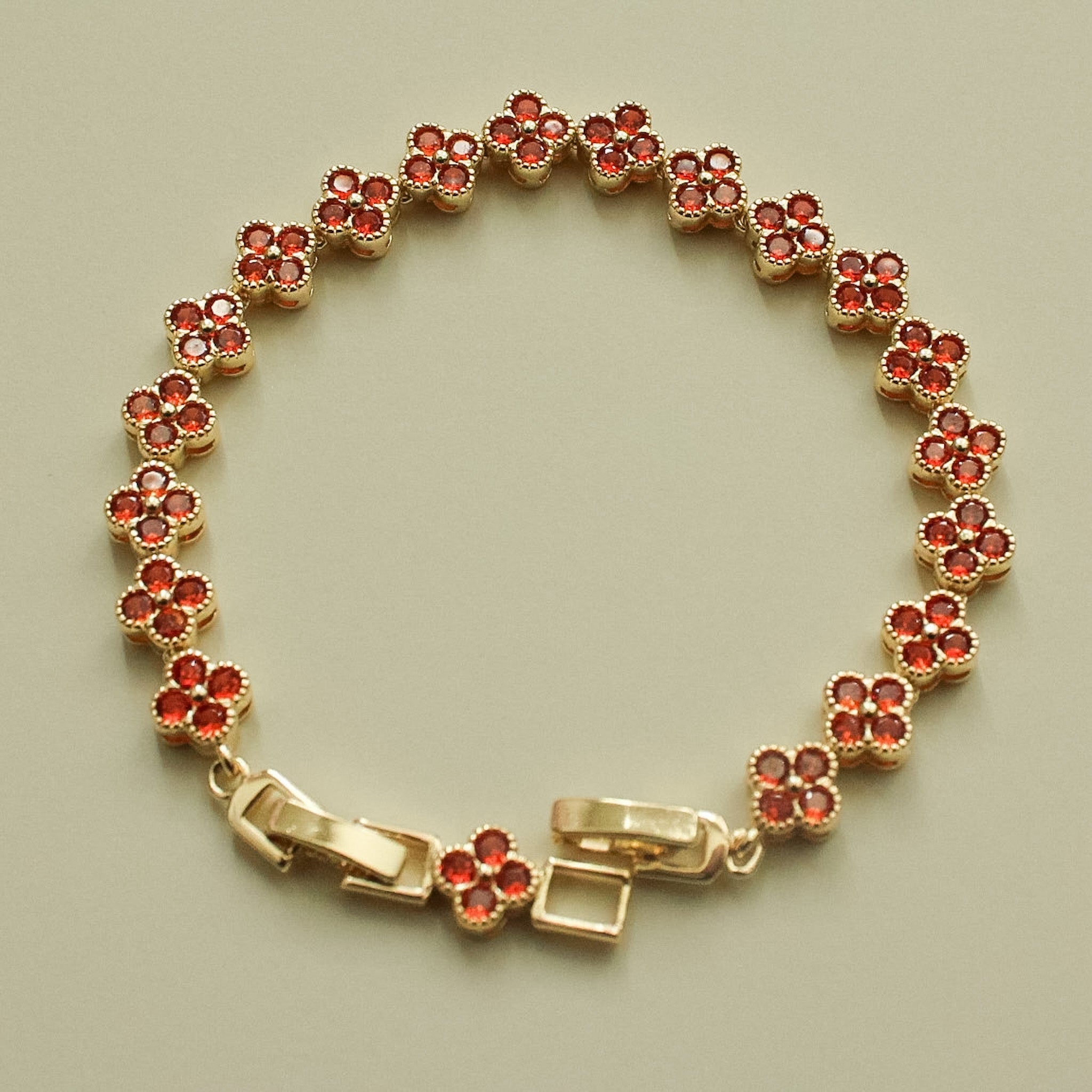 Gold-tone bracelet with red round CZ flower links and central toggle clasp