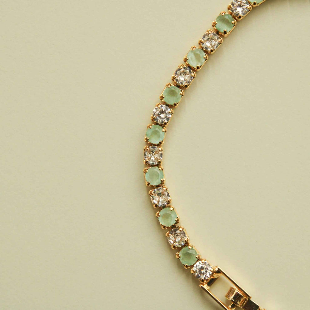 Gold-tone tennis bracelet with seafoam green stones and clear round CZ links