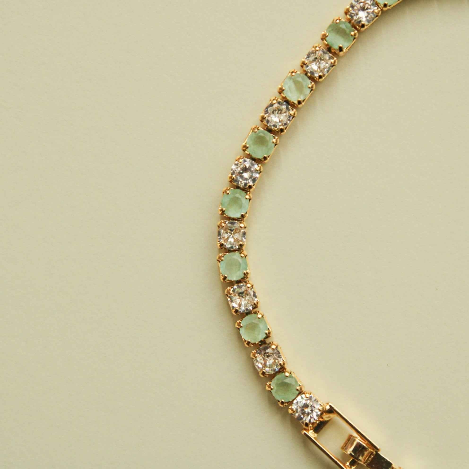 Gold-tone tennis bracelet with seafoam green stones and clear round CZ links