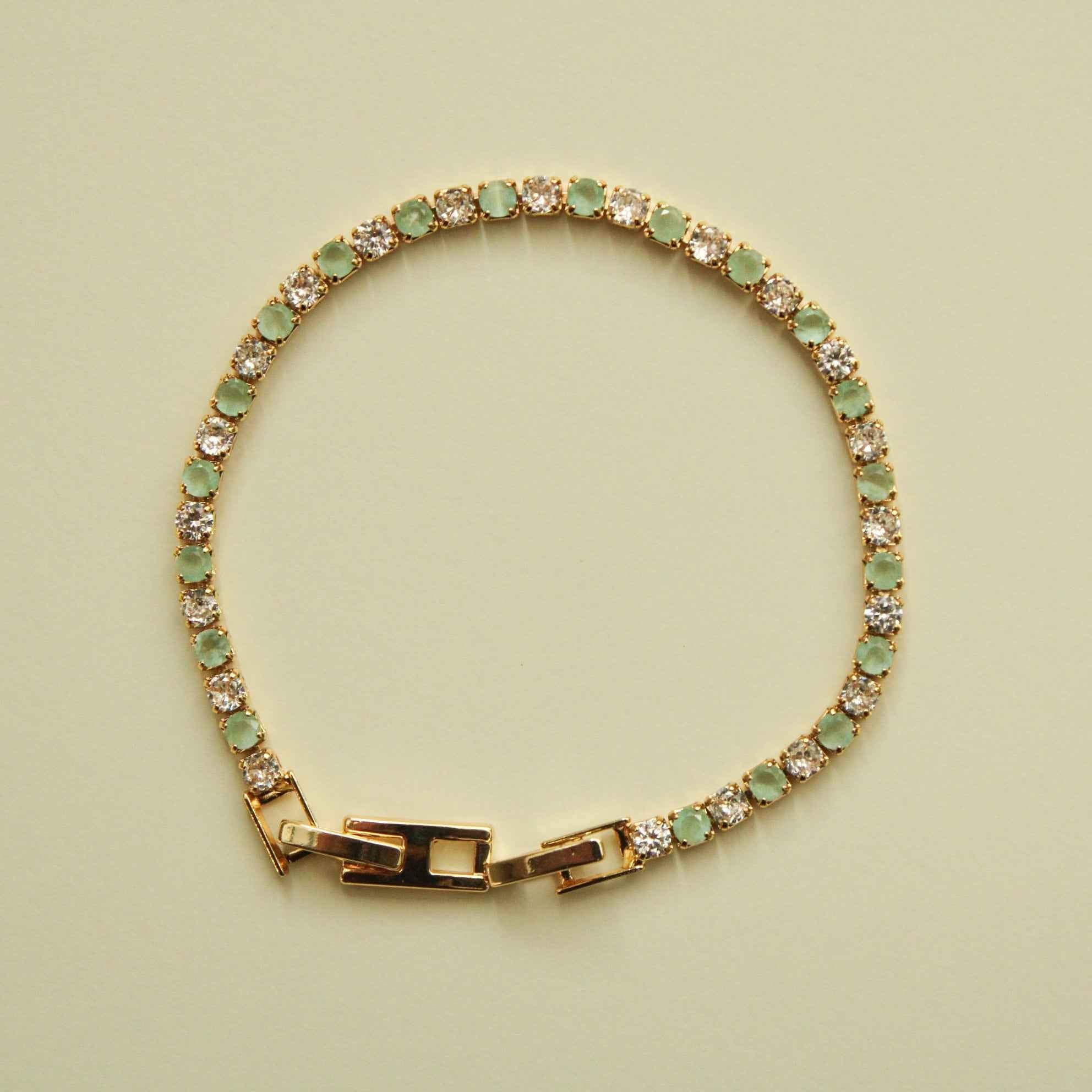 Gold-tone tennis bracelet with seafoam green stones, clear CZ accents, hinged clasp