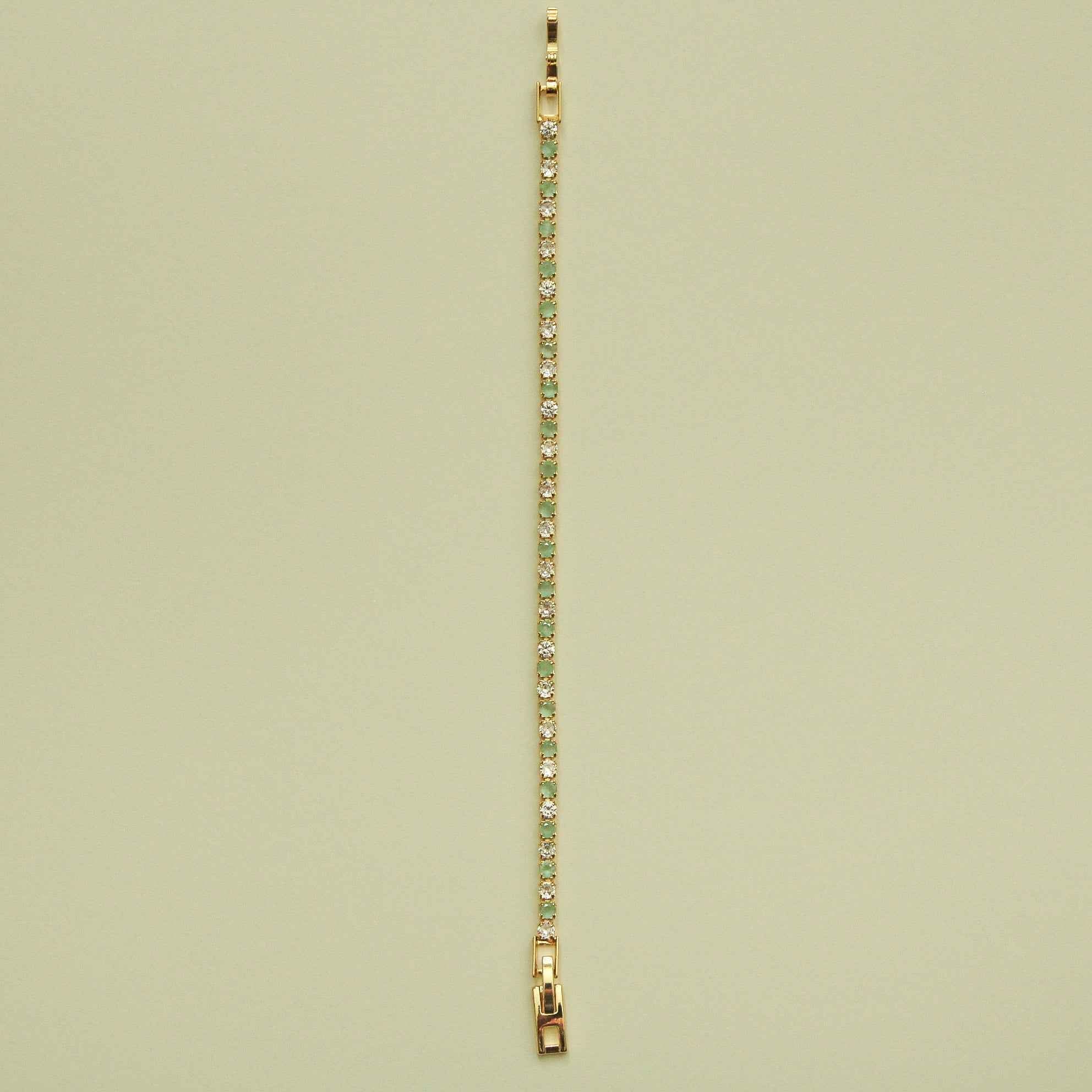 Gold-tone tennis bracelet with a straight row of seafoam green stones and CZs