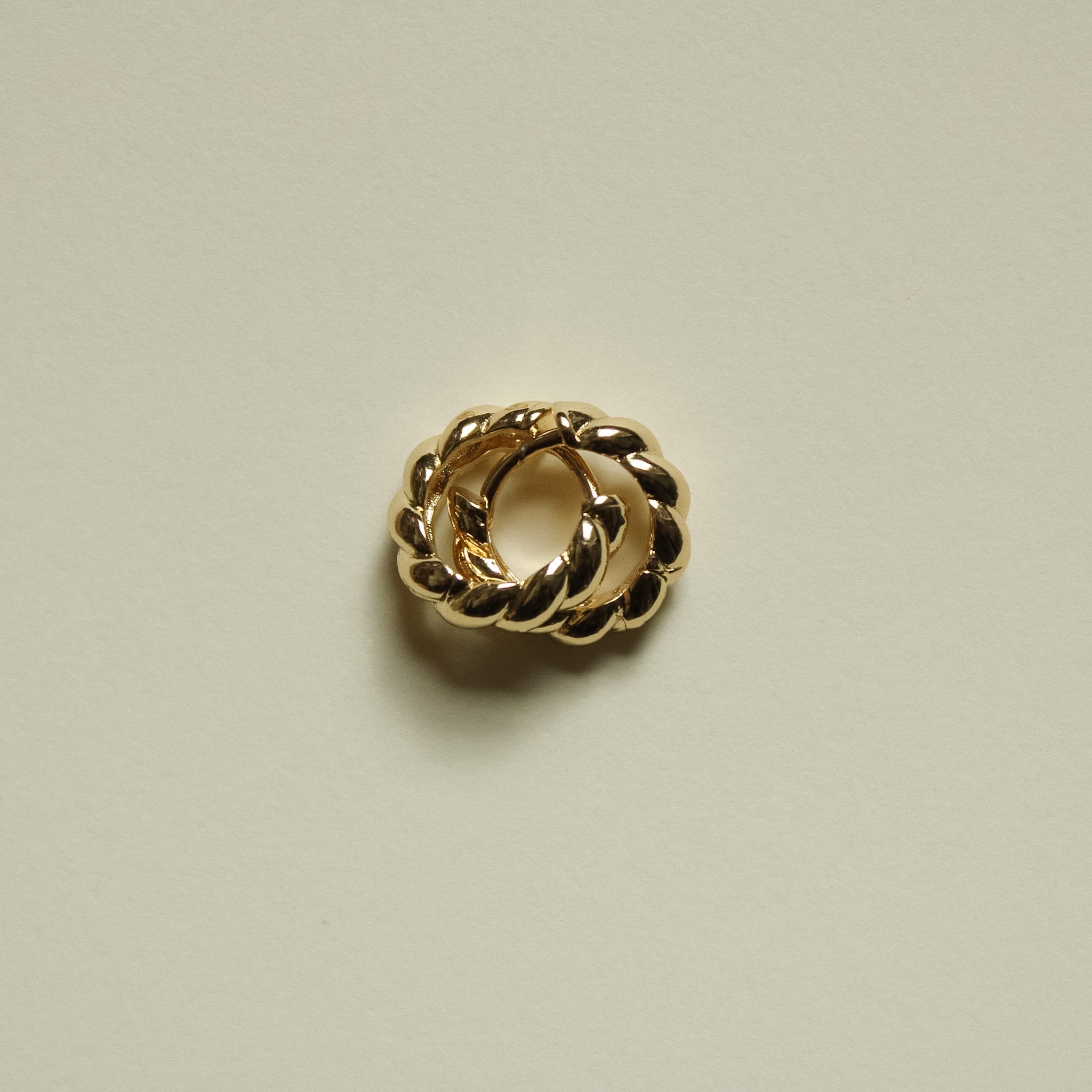 Gold-tone twisted huggie hoop earring with interlinked oval twists